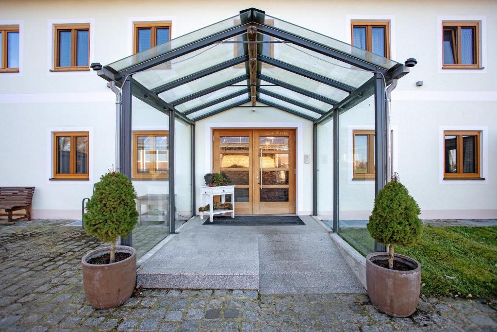 a glass entrance to a building with two potted trees at Haus am Hof in Kirchseeon