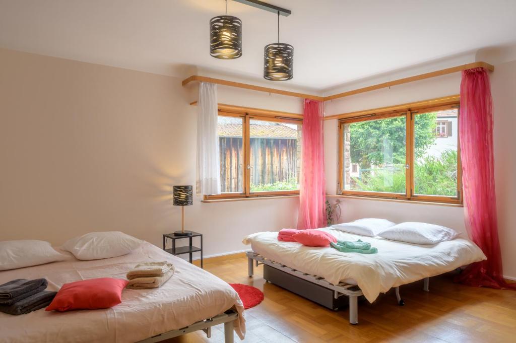two beds in a room with two windows at Gîte De Pipala in Mittlach