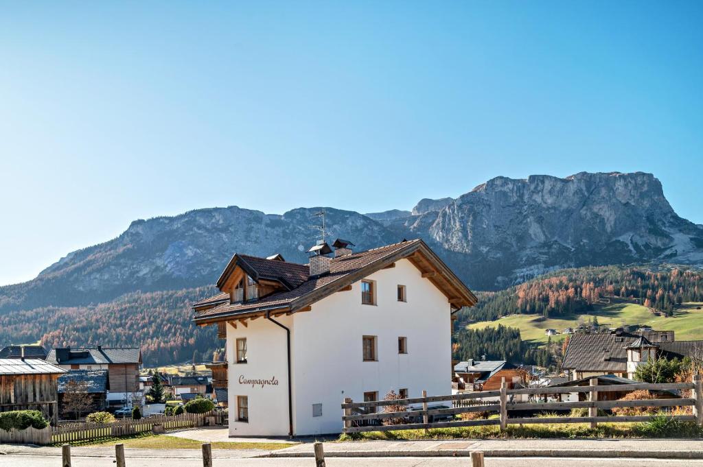 a small white building with mountains in the background at Apartments Campagnola in Badia