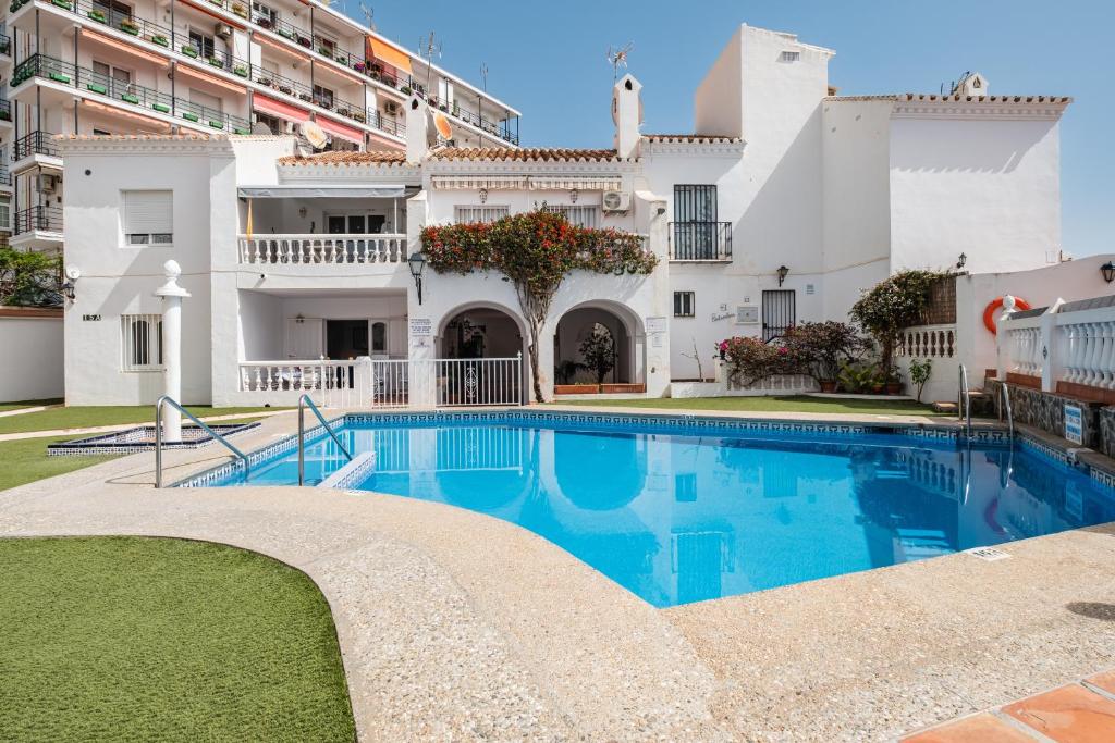 a swimming pool in front of a large white building at Bright spacious 1 bed apartment in Nerja