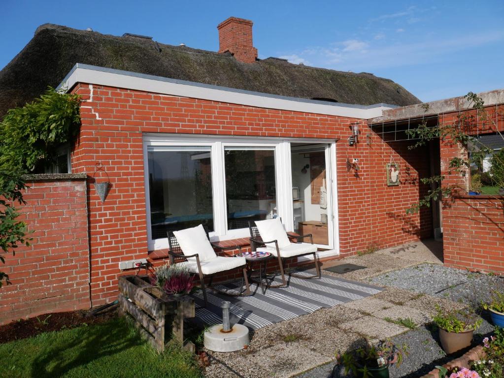 a patio with chairs and a table in a brick house at Ferienwohnung Unter Reet in Risum-Lindholm