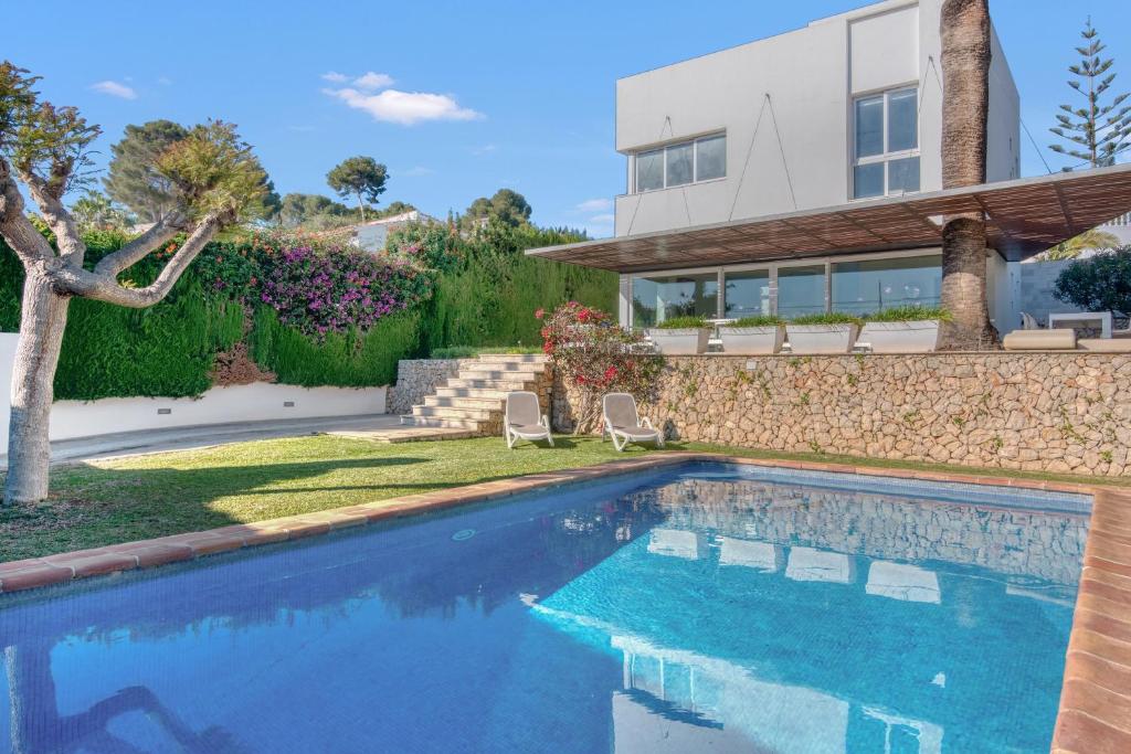 a swimming pool in front of a house at Traviata in Cap Blanc