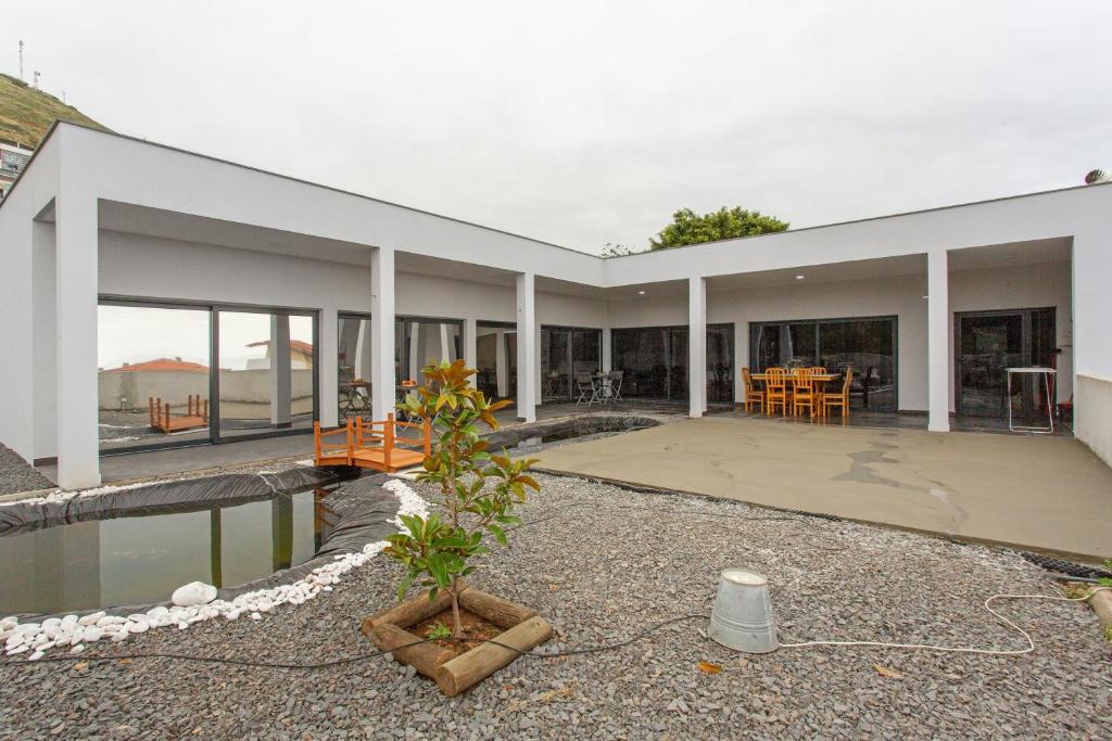 a large white building with a patio and water at Paraiso Madeira - Suites in Gaula