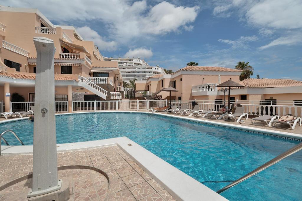 a swimming pool at a resort with chairs and condos at Seaview las Americas in Adeje