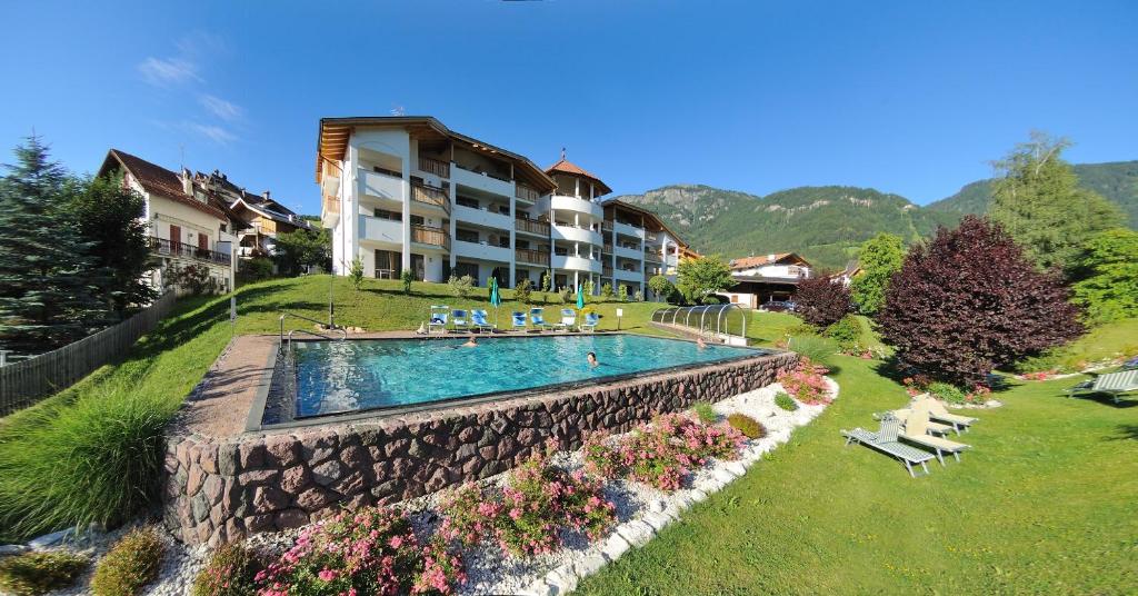 a resort with a swimming pool and a building at Residence Nussbaumer in Siusi