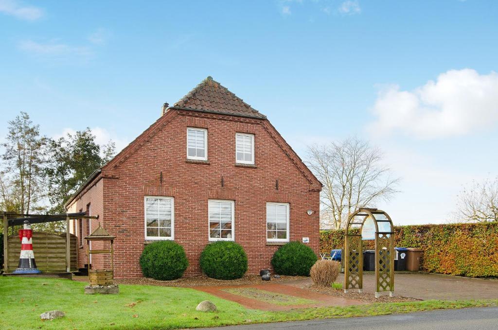 a red brick house with a playground in front of it at Ferienwohnungen Schmitz in Wangerland