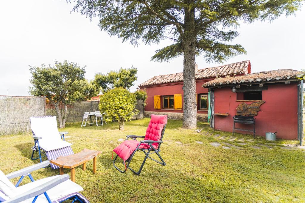 a group of chairs in a yard with a red house at El Colono El uncar in Castrejón de la Peña