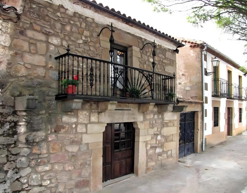 a stone building with a balcony and a door at Las Frascuelas Habitaciones in Almajano