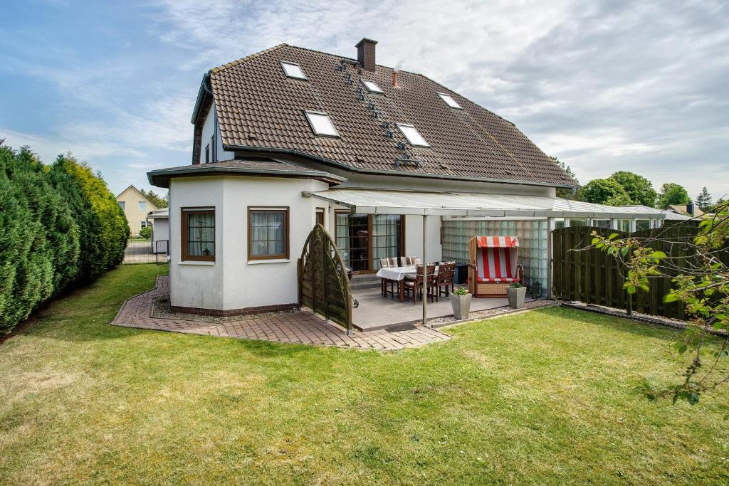 a small white house with a patio in the yard at Ferienwohnung K Schröder in Sundhagen-Niederhof