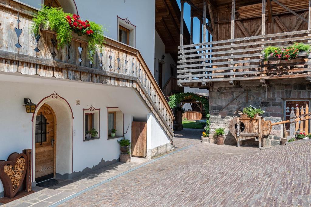 a cobblestone street in a building with flowers on the windows at Schildberghof Panorama in Kastelruth