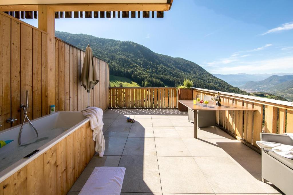a bathroom with a tub and a table on a deck at Sonnleiten Sonnenparadies in Collepietra