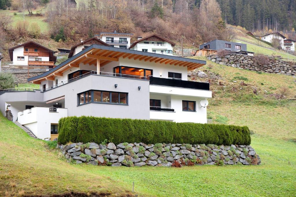 a house on a hill with a stone wall at Apart Löffler in Kappl