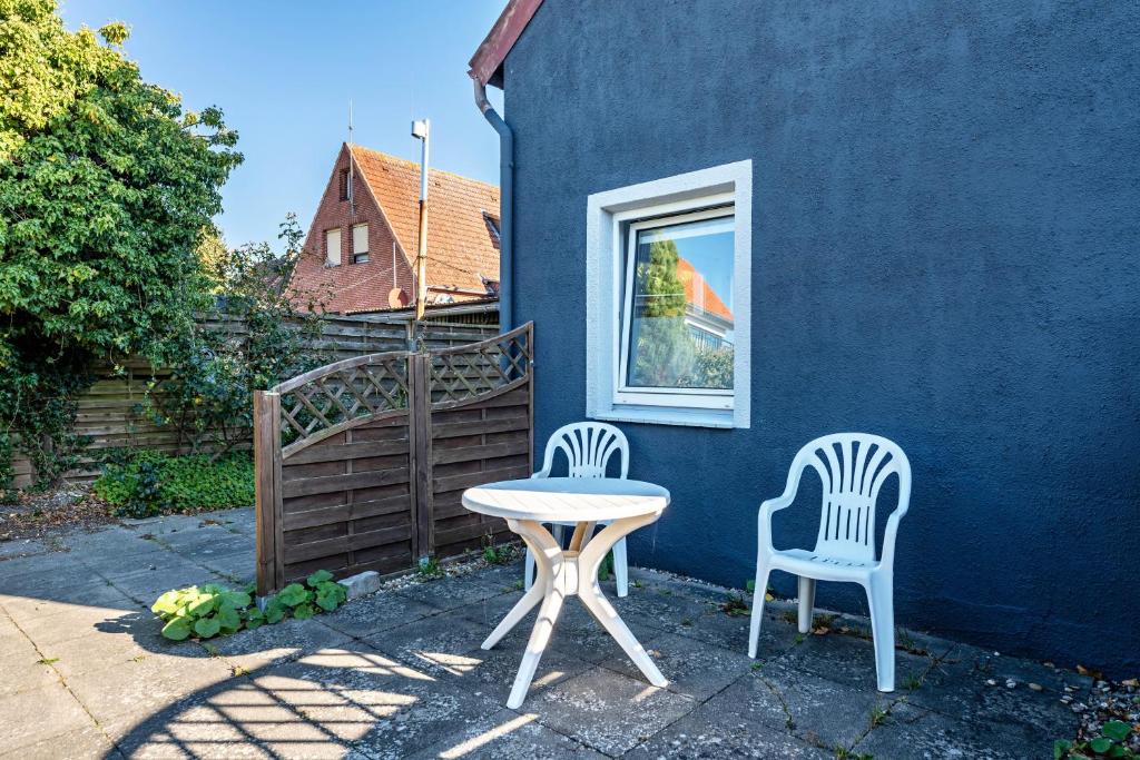 two chairs and a table in front of a blue house at Insel Koje 1 in Fehmarn