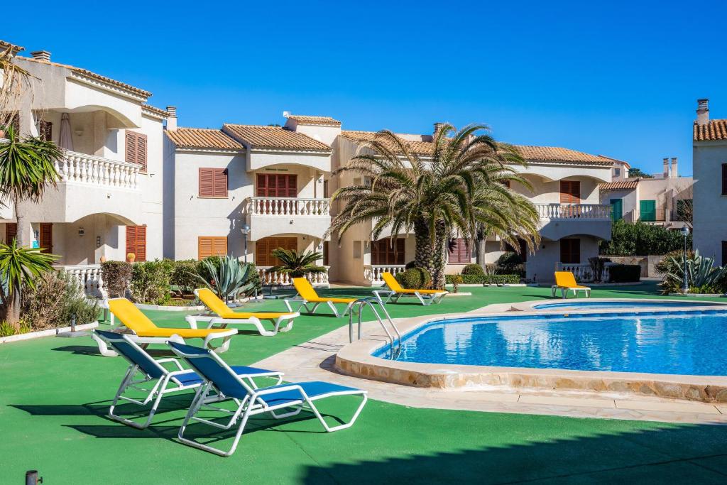 a resort with a pool and chairs and palm trees at Can Nogueras in Cala Ratjada