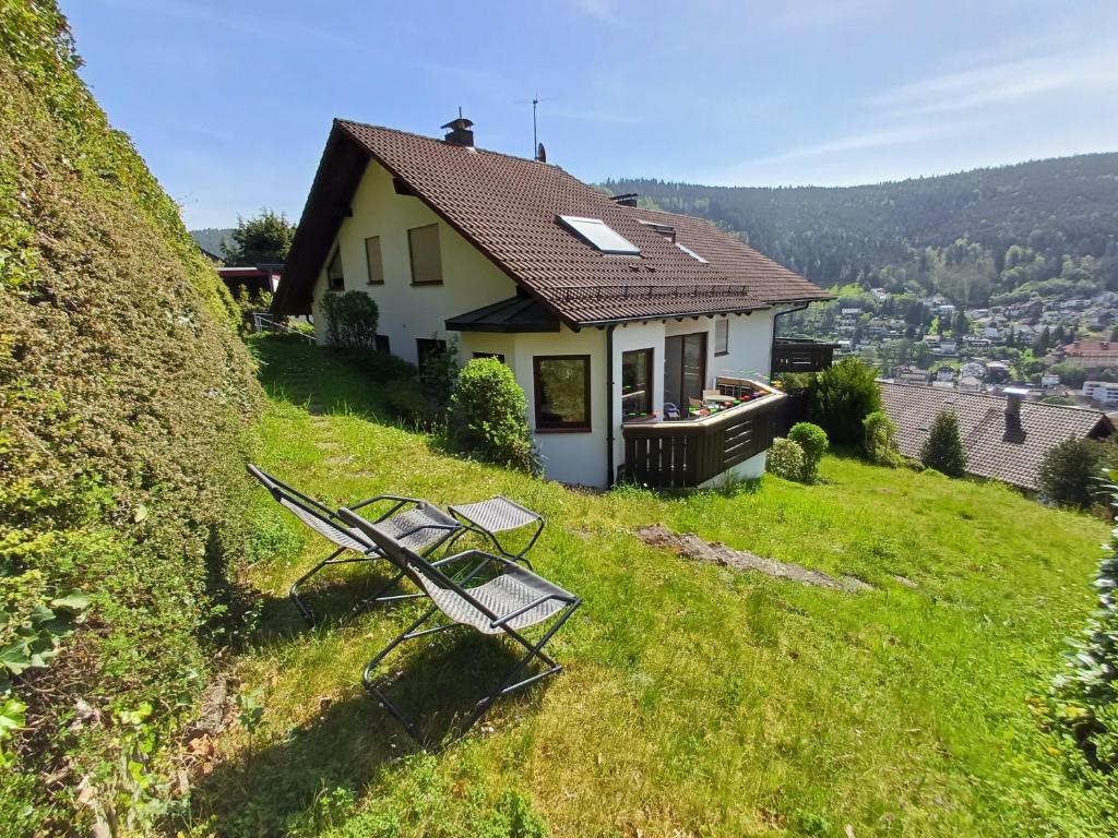 a house on a hill with two chairs in the grass at Ferienwohnung Panoramablick in Bad Wildbad
