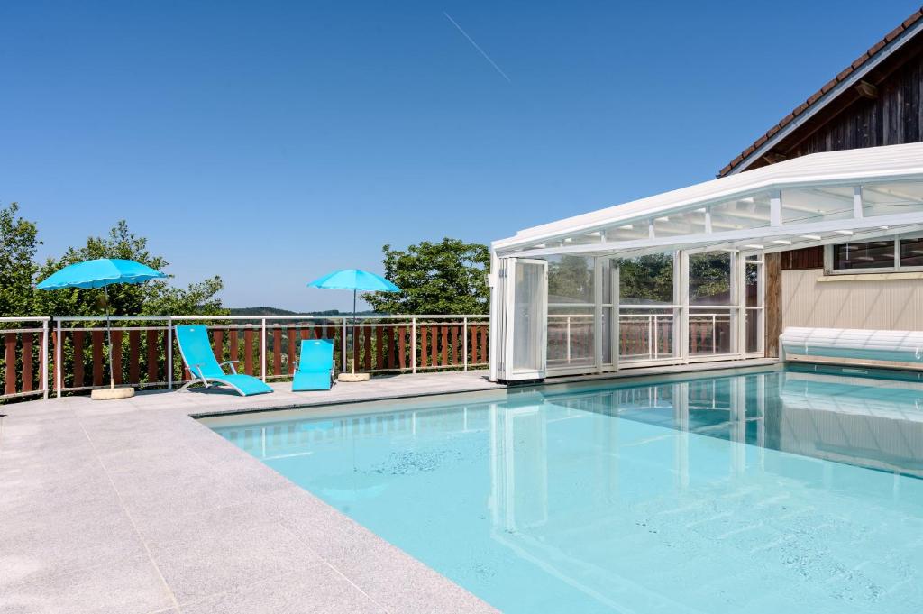a swimming pool with two chairs and an umbrella at Chalet les moraines 8 in Le Tholy