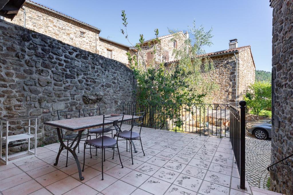 a patio with a table and chairs next to a stone wall at Typical House Completely Renovated in Saint-Alban-dʼAy
