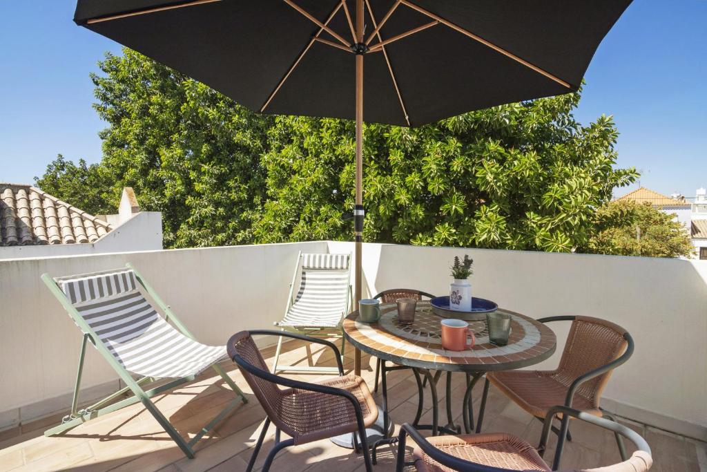 a table with chairs and an umbrella on a patio at Casa Do Alto in Tavira