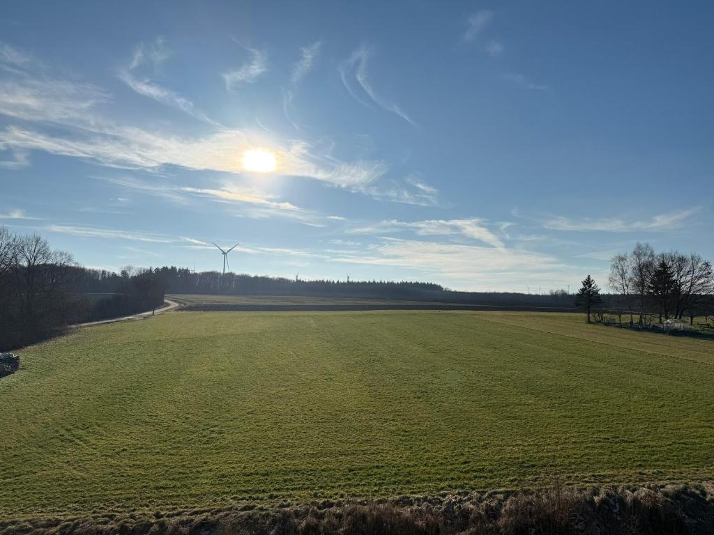 a large green field with the sun in the sky at Ferienwohnung Waldblick Alterkülz in Alterkülz