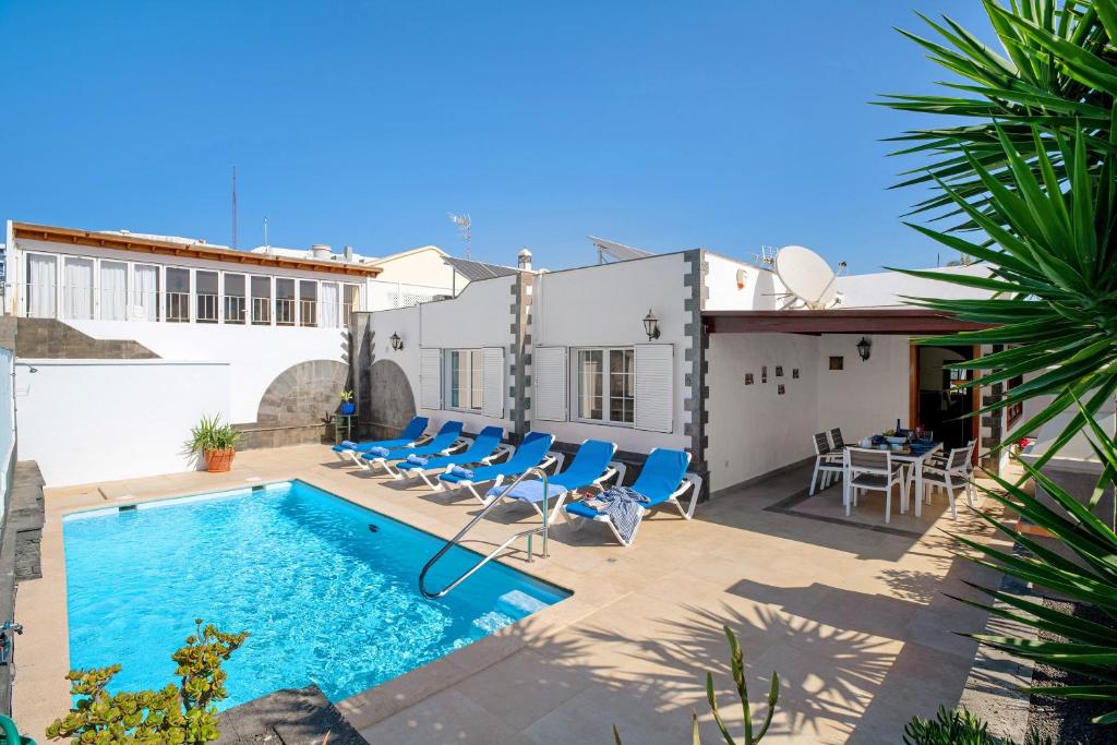 a villa with a swimming pool and chairs at Villa Muñoz in Puerto del Carmen