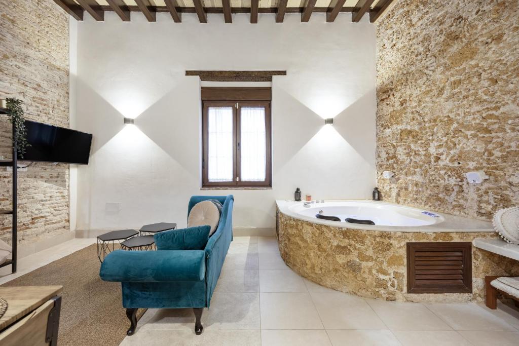 a bathroom with a large tub and a blue chair at Bella Encantada in Cádiz