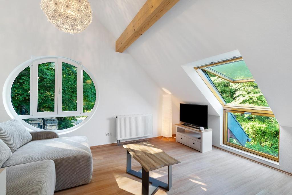 a living room with a couch and two large windows at Ferienwohnung am Hirschfelsen in Bühlertal