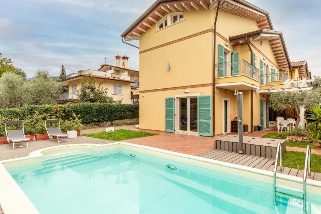 a villa with a swimming pool in front of a house at Relax in Villa - Versilia in Massa
