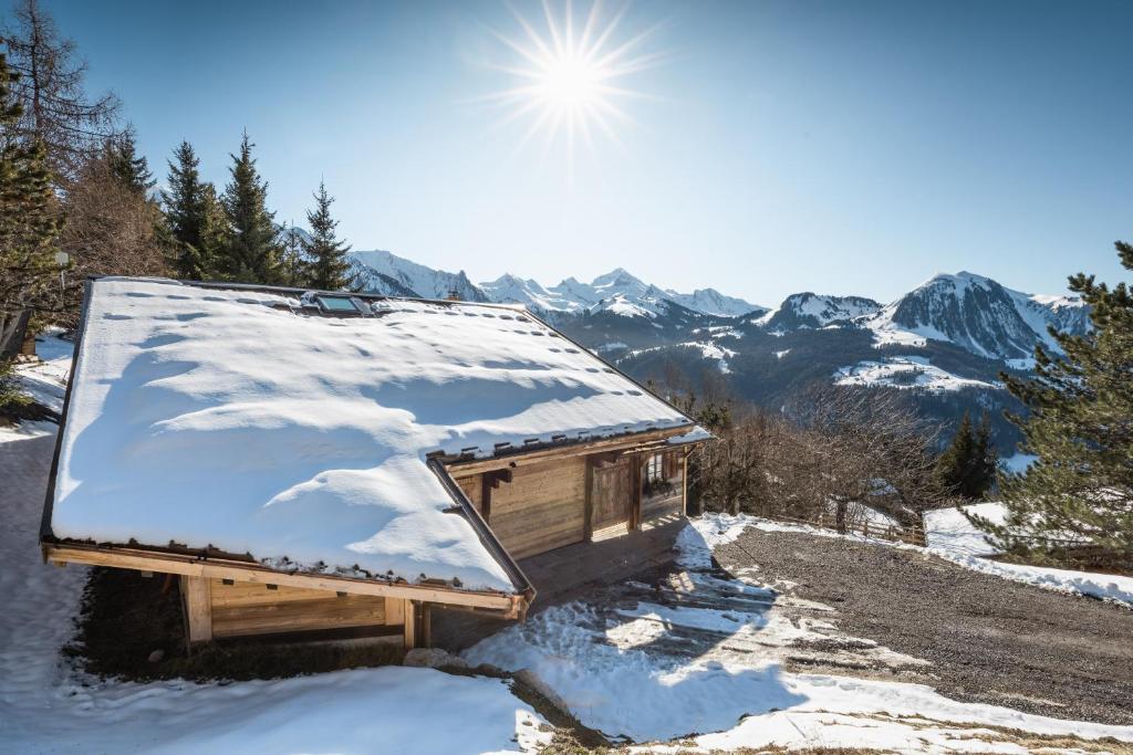 a cabin with snow on the roof in the mountains at Chalet Karavi in Manigod