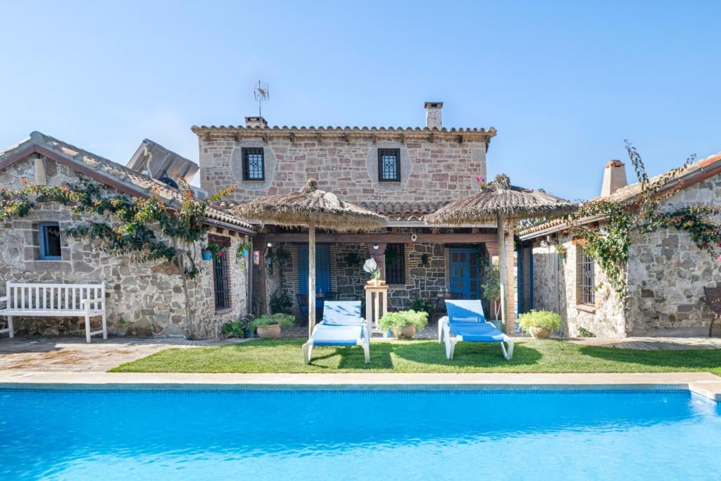 a house with two blue chairs and a swimming pool at Casas Alfonso y Laura in Conil de la Frontera