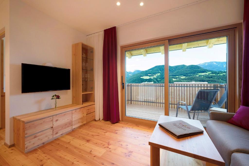 a living room with a television and a large window at Teutenhofer Zwetschge in Feldthurns