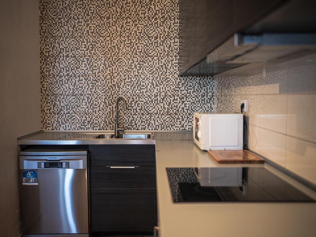 a small kitchen with a sink and a microwave at Casa na Vila T2 in Fuzeta