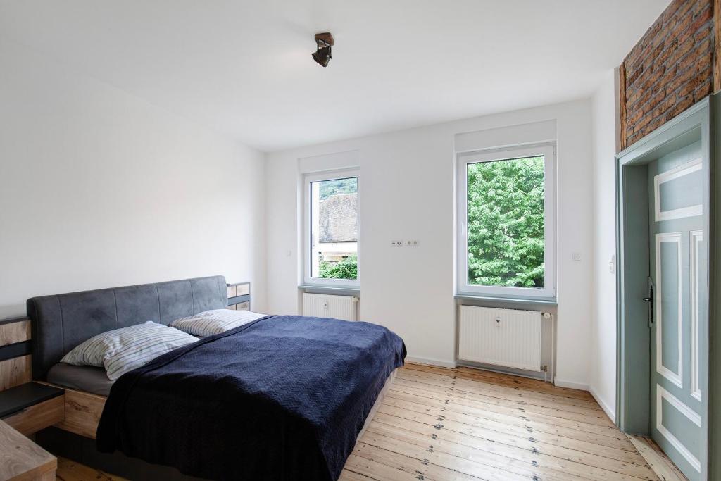 a bedroom with a bed and two windows at Ferienwohnung Rheinschlendern in Rüdesheim am Rhein