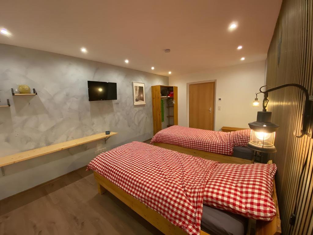 a room with two beds and a tv on the wall at Bergwiesnblick Apartments in Bärenstein