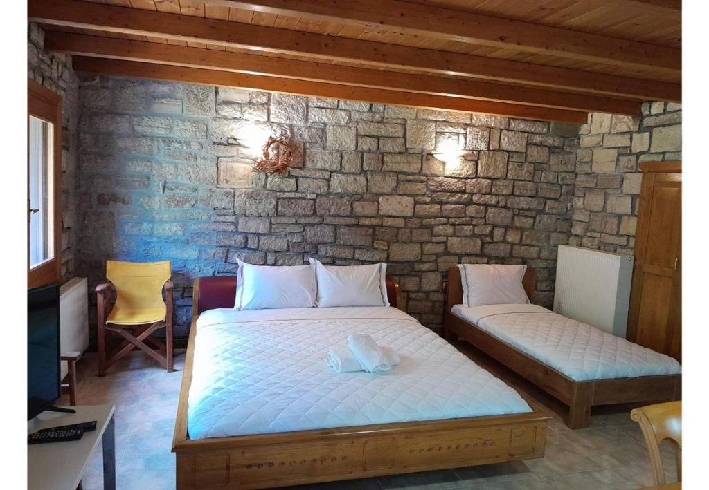 a bedroom with a bed and a stone wall at Tsarouxi village 2 in Karditsa
