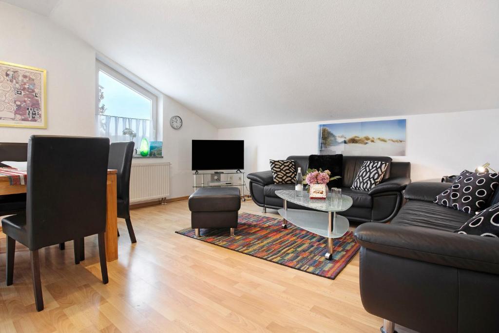 a living room with couches and a table and a television at Haus A Cappella B6 in Binz