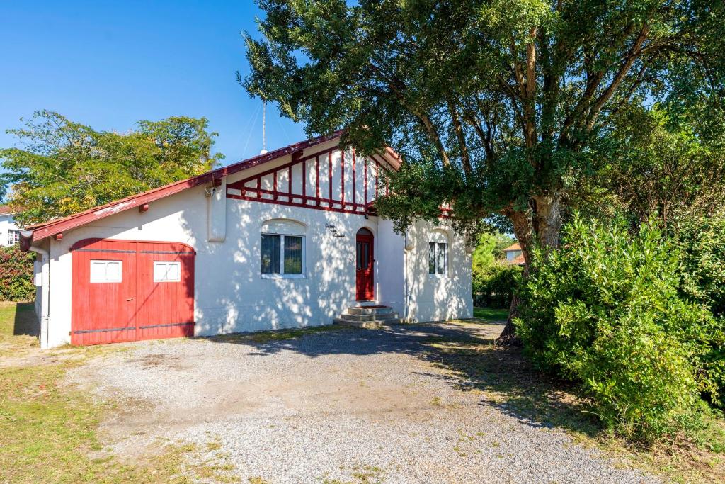 a white house with a red door and a tree at Maison Cosy, Lac et Plages in Hossegor