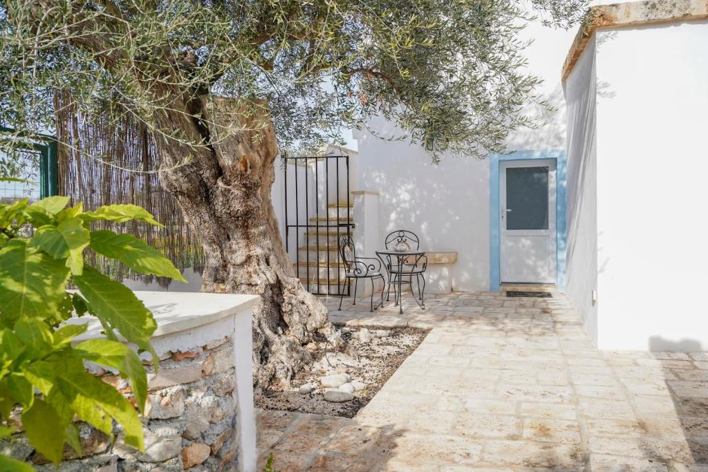 a tree in front of a building with a table at Casina delle Rose - Scirocco in Polignano a Mare