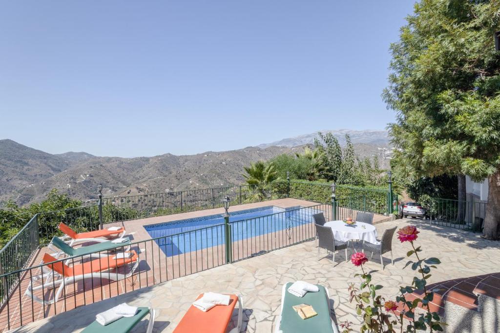 a pool with a table and chairs next to a house at Casa las Olivas in Sayalonga