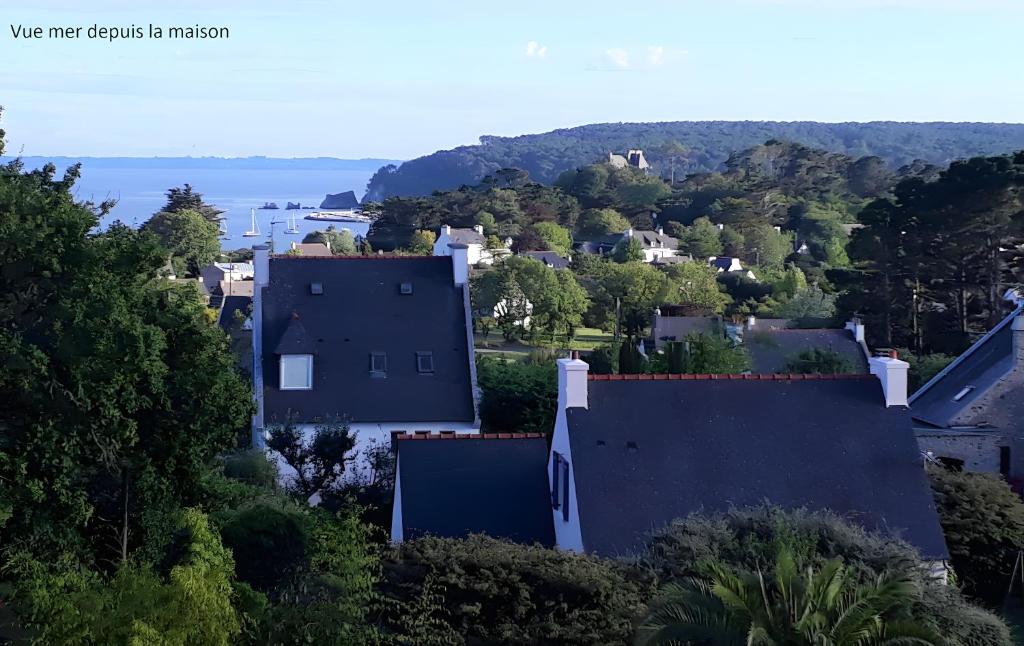 a house on a hill with the ocean in the background at Maison quartier Porzic vue Mer in Crozon