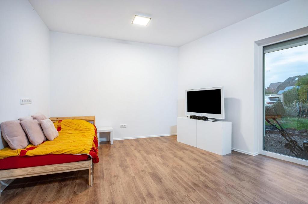a white room with a bed and a flat screen tv at Cozy Ground Floor Apartment in Bremen