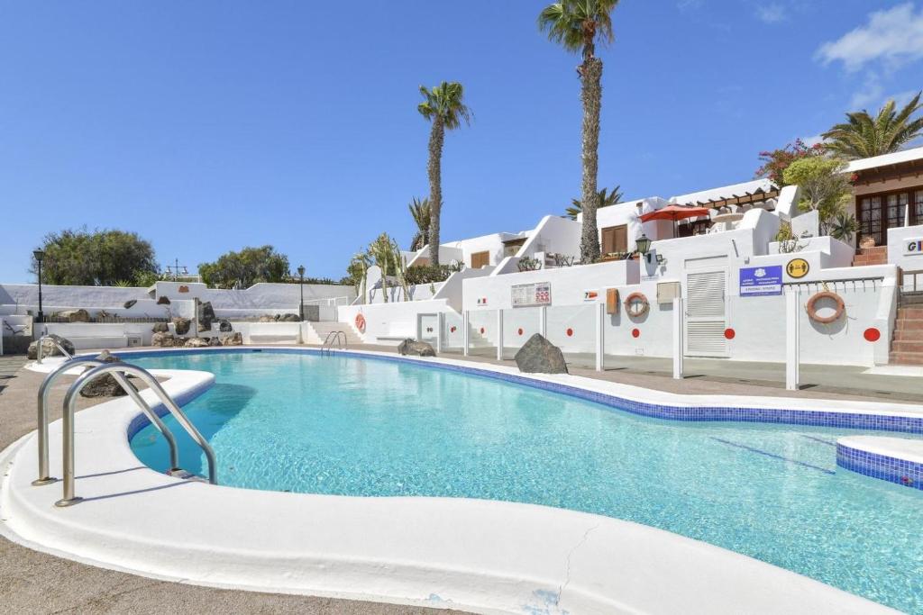 a swimming pool at a resort with palm trees at Puerto Chico 1 in Playa Blanca