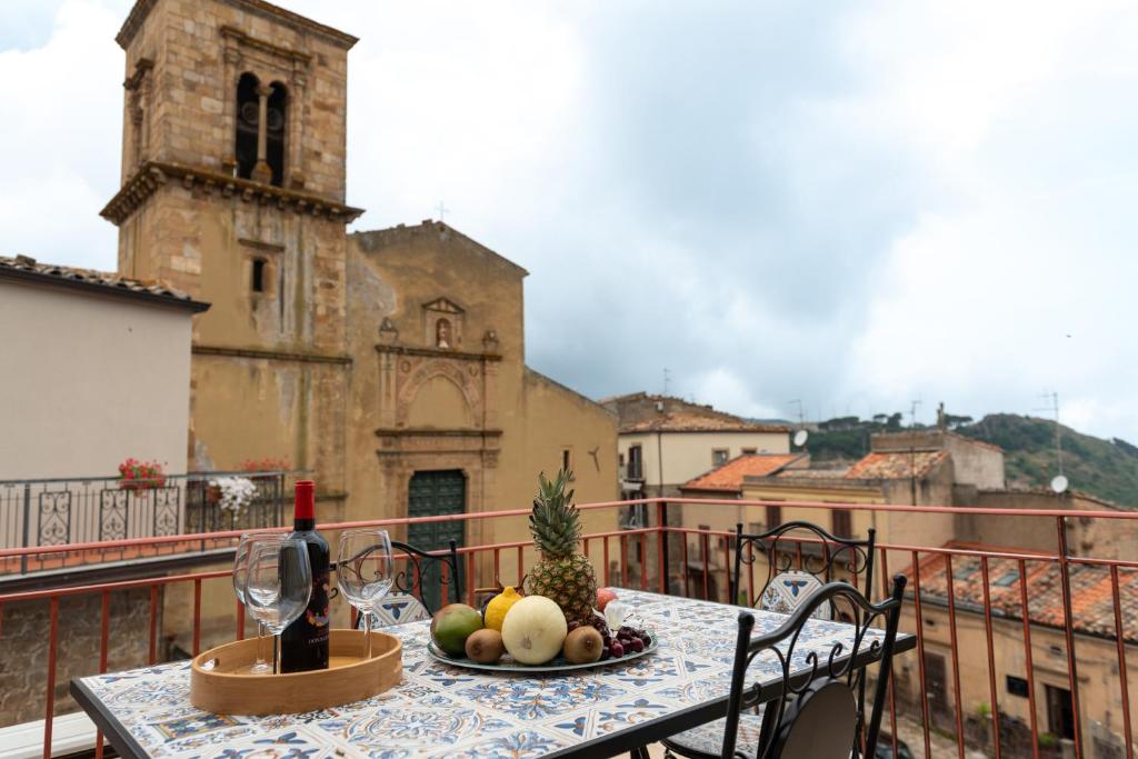 a table with a bottle of wine and fruit on a balcony at Vico degli Orti in Mistretta
