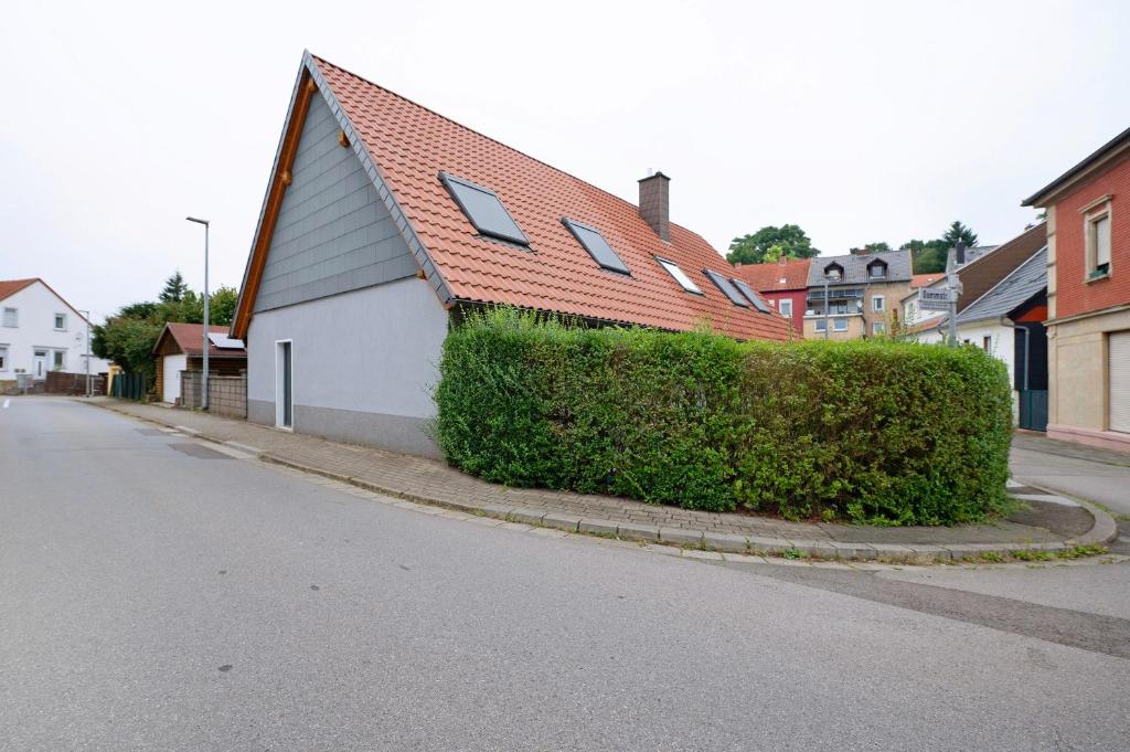 a house with a hedge next to a street at Fewo Weber in Sankt Ingbert