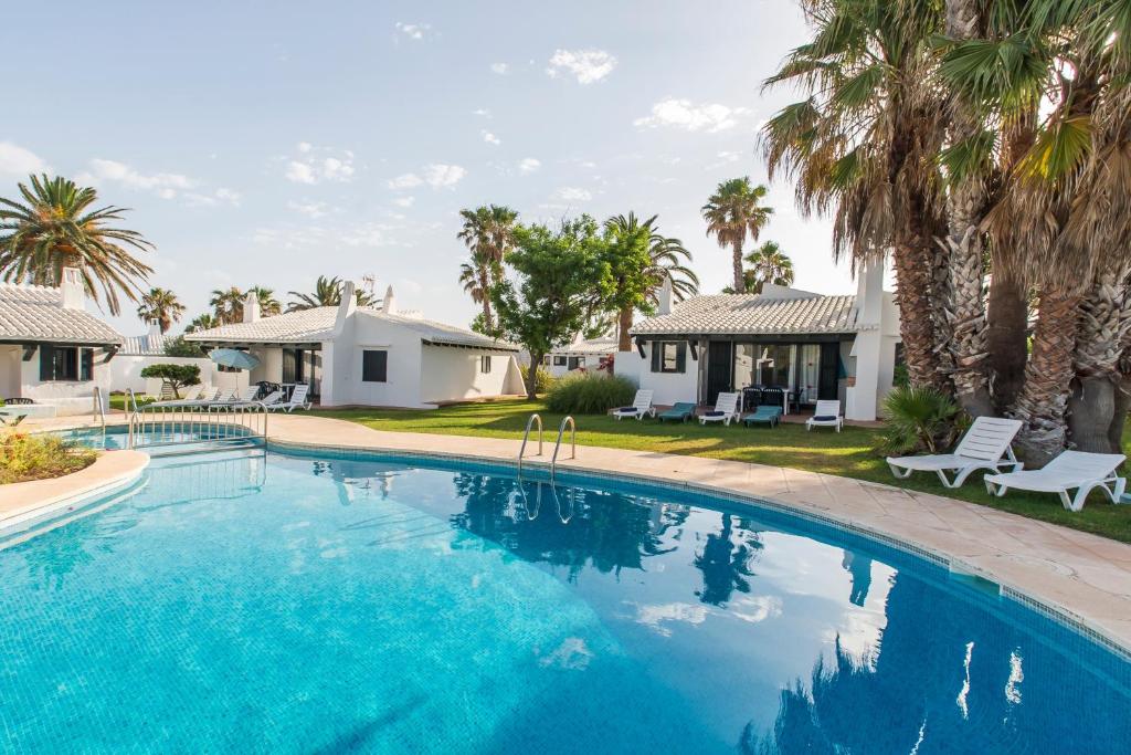 a swimming pool with palm trees and a house at Casa 6 U en Complejo Binisafua in Binisafua