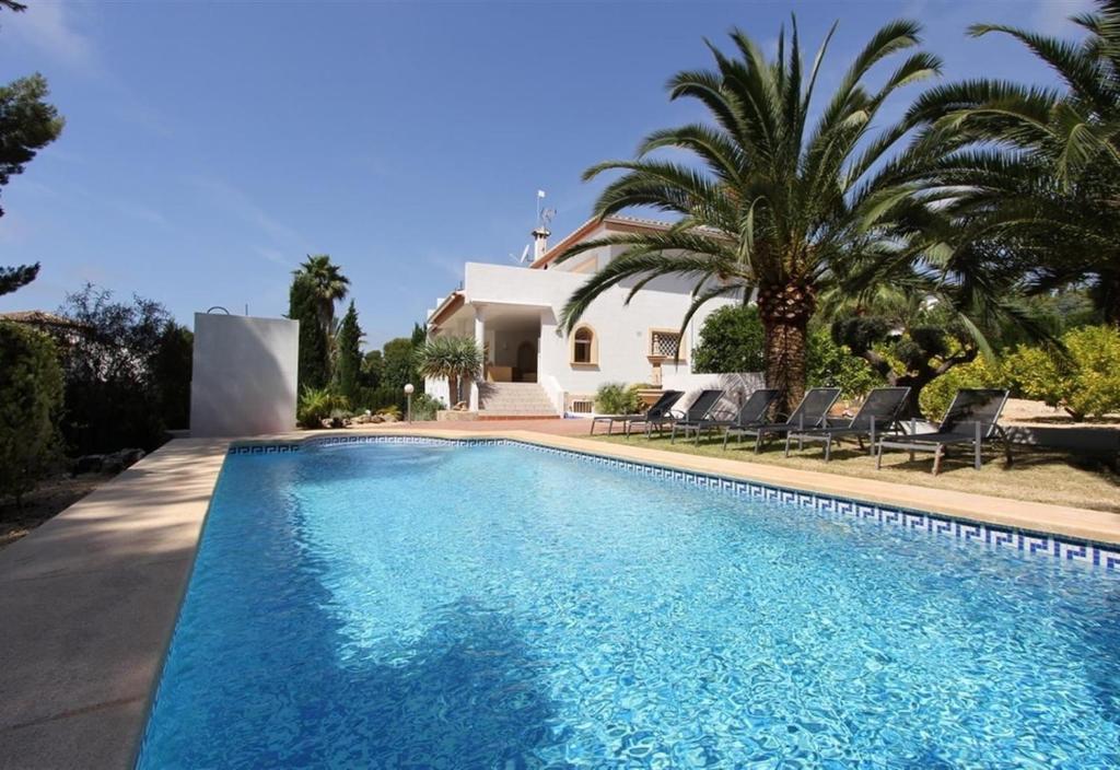 a swimming pool in front of a villa at Gloriann in Moraira