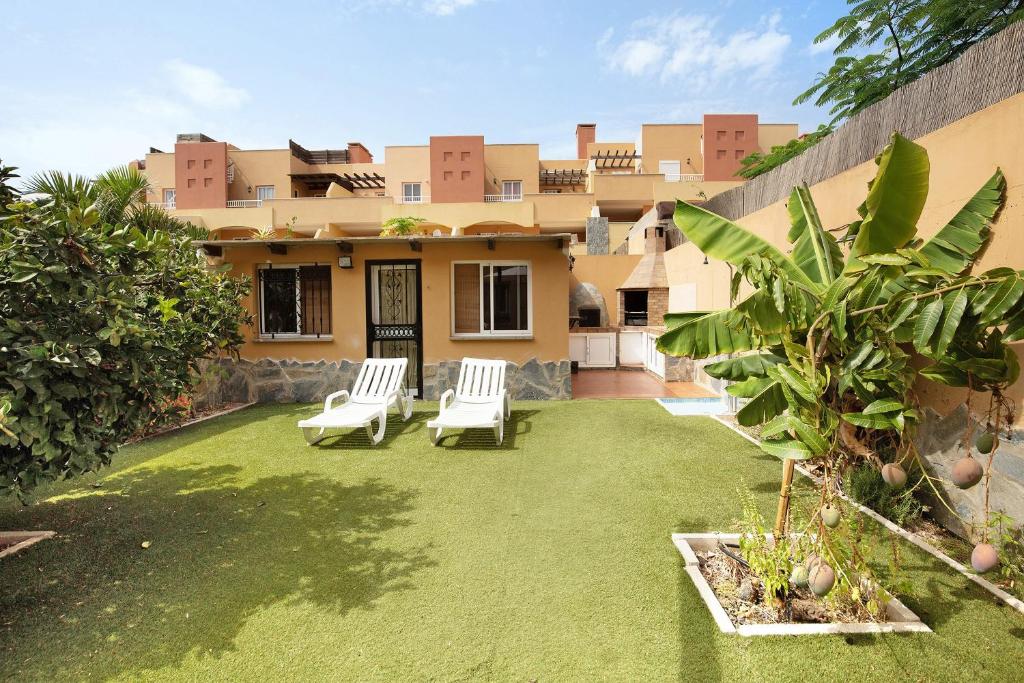 a yard with two lawn chairs and a house at Casa Carlos in Corralejo