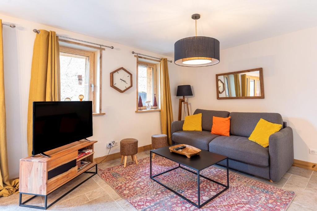 a living room with a couch and a tv at Lodge Alouette in Champagny-en-Vanoise