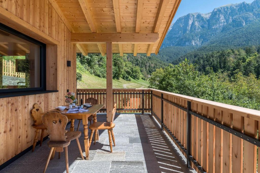 a wooden deck with a table and chairs and mountains at Chalet Kasch Apartment Berg in Völs am Schlern
