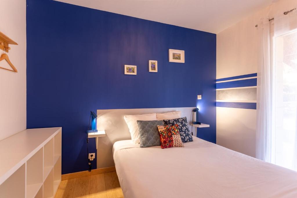 ein Schlafzimmer mit einer blauen Wand und einem Bett in der Unterkunft Chambre - Gentiane in Aroue