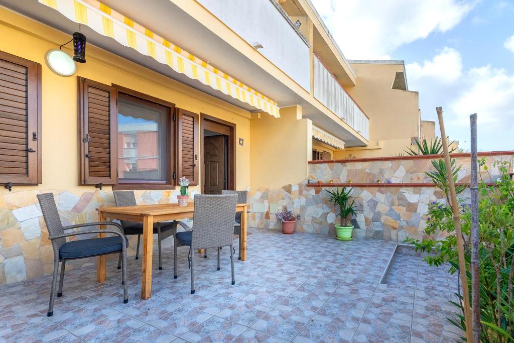 a patio with a wooden table and chairs at Albachiara Sul Mare in Porto Torres